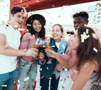 group of friends drinking Champaign and laughing together on boat with confetti