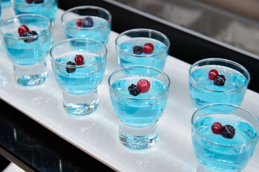 Blue jelly with berries in a glass on a white plate